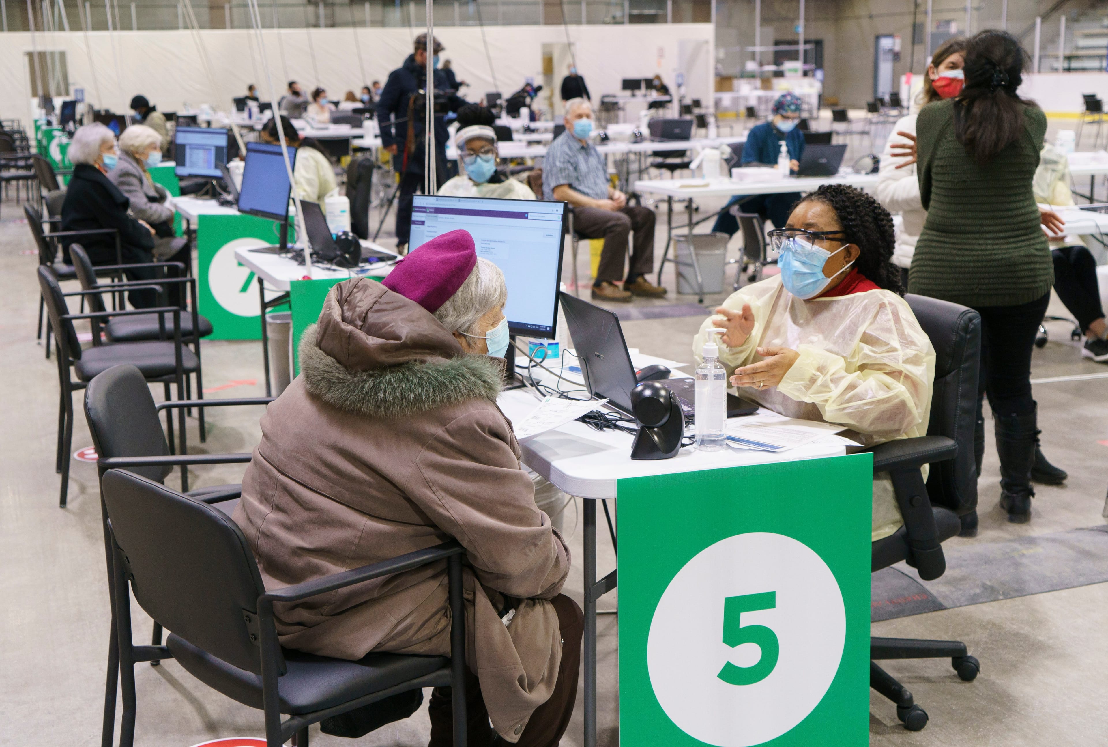Seniors register at a COVID-19 vaccination clinic in a hockey arena in Montreal. (Paul Chiasson/CP)