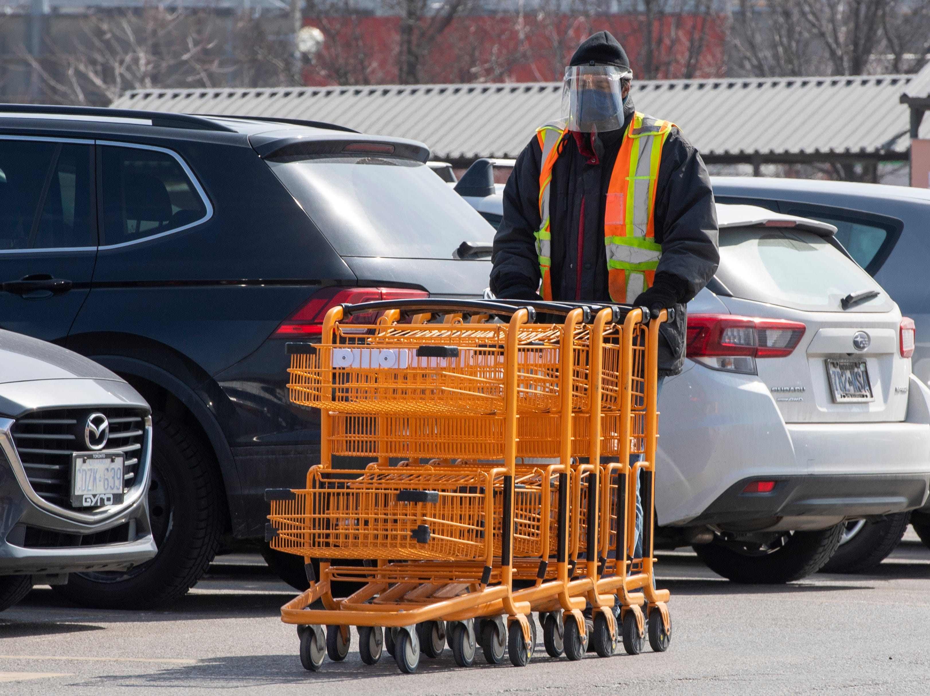 An essential worker gathers shopping carts in a grocery store parking lot in Toronto on Wednesday, March 17, 2021. THE CANADIAN PRESS/Frank Gunn