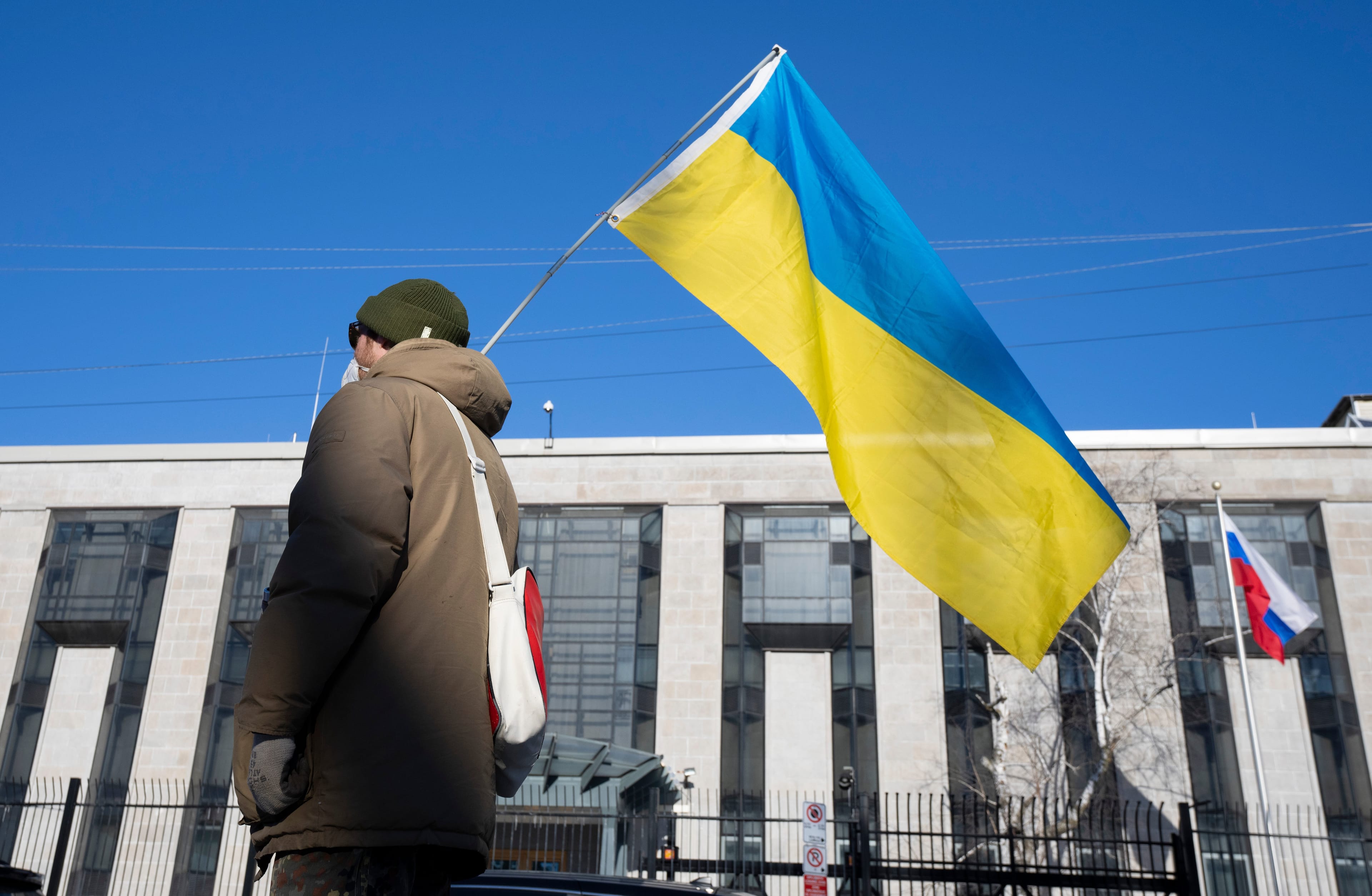 A pro-Ukrainian supporter waves the country's flag outside the Russian embassy on Feb. 24, 2022 in Ottawa (Adrian Wyld/CP)