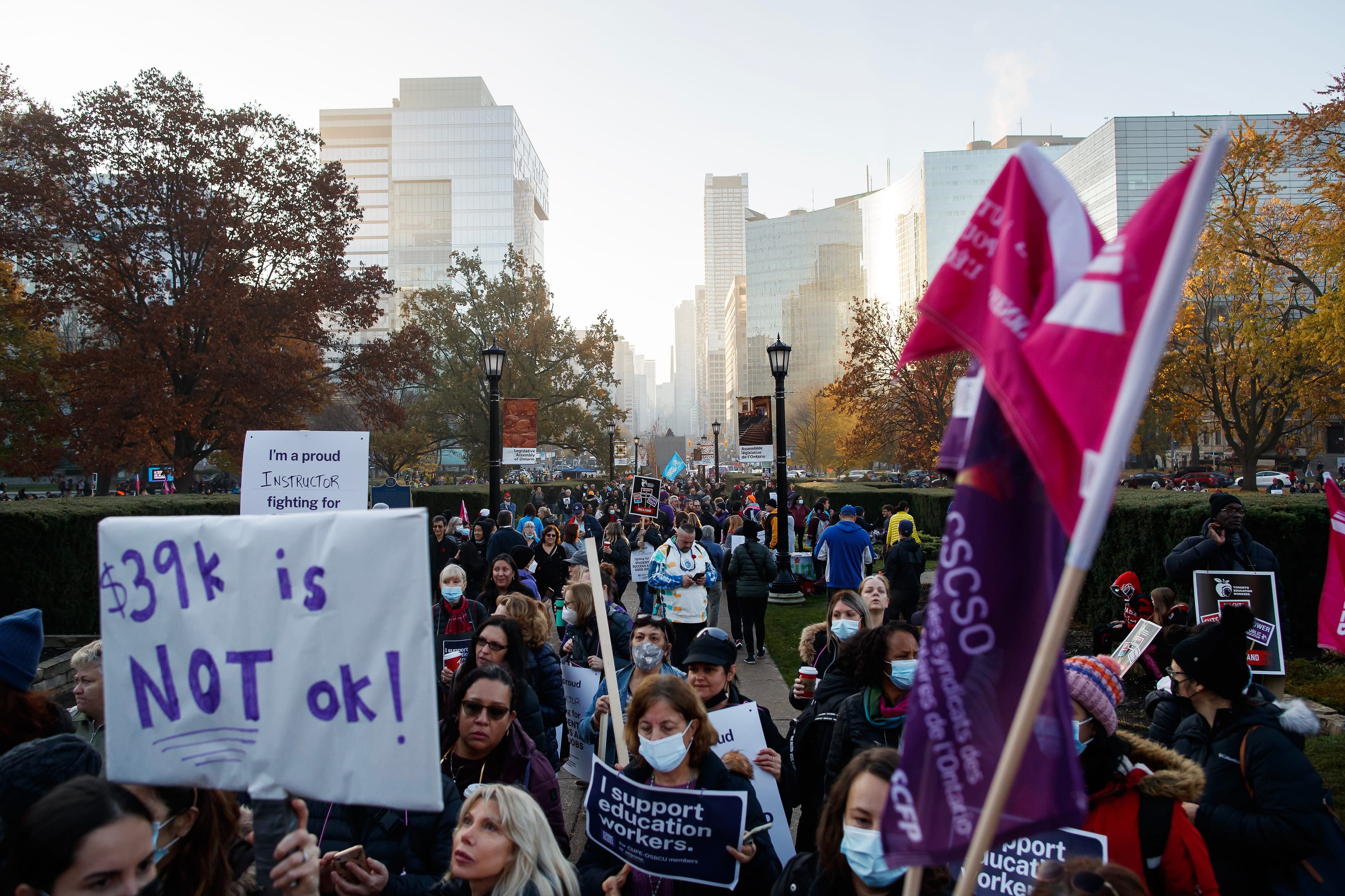 CUPE Ontario members and supporters wave signs and flags as they demonstrate outside of the Queen's Park Legislative Building in Toronto, Friday, Nov. 4, 2022. THE CANADIAN PRESS/Cole Burston
