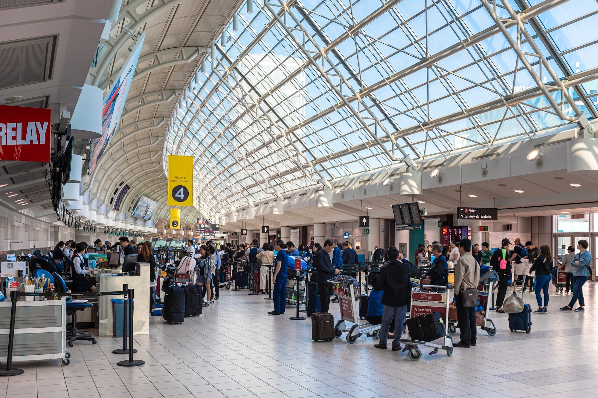 The departures area of Pearson airport with about 100 people waiting to go to boarding gates.