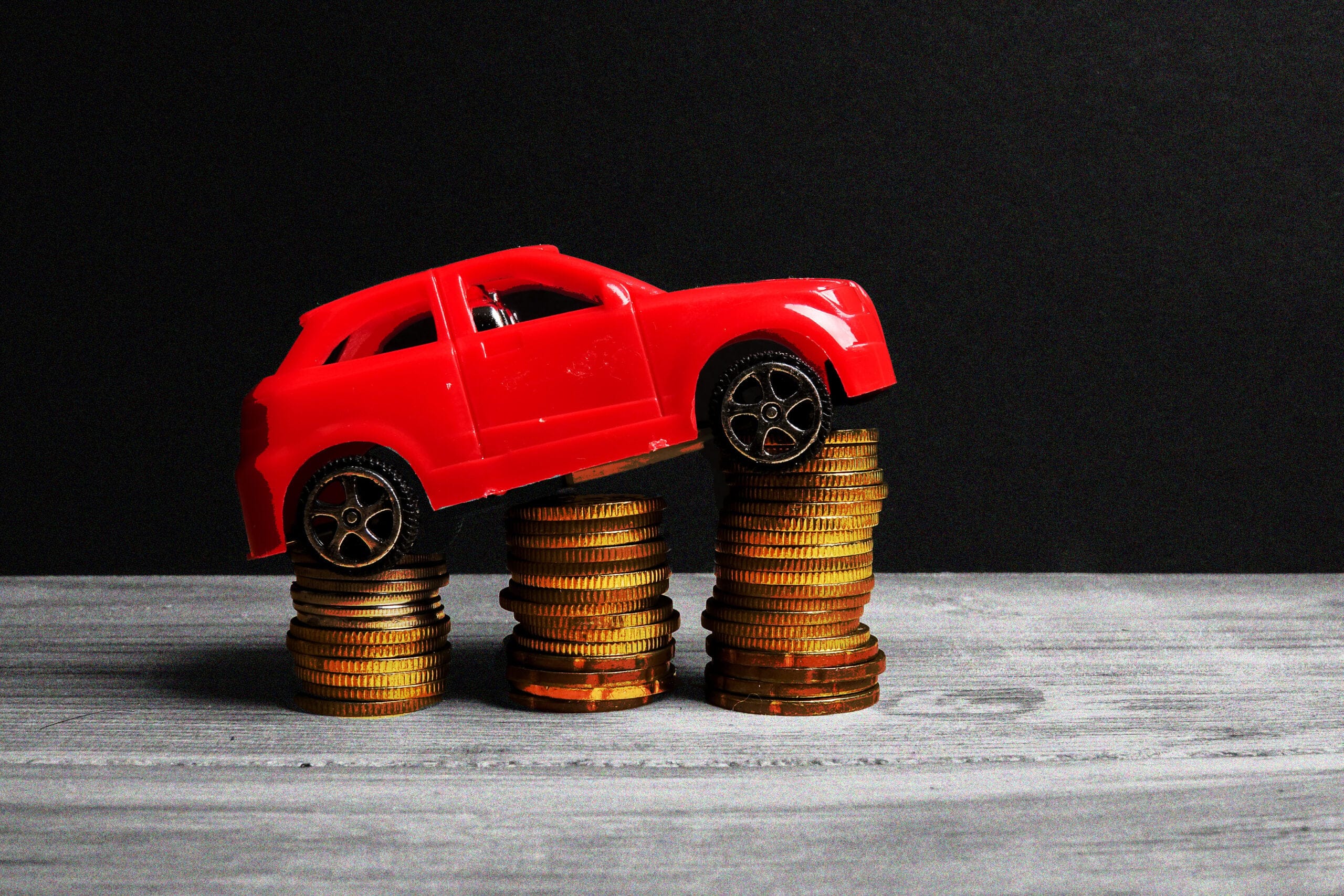 A miniature red car sitting on three stacks of pennies