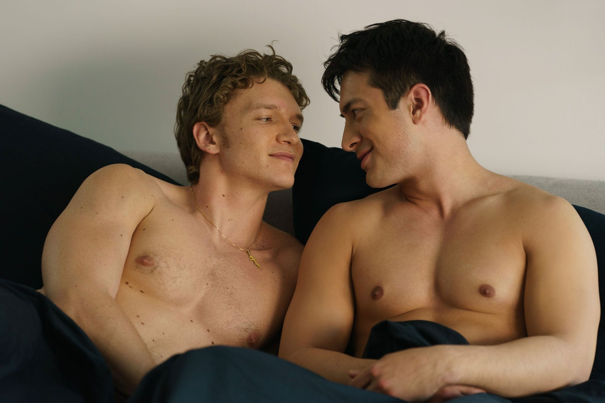 The two male leads of Heated Rivalry, shirtless and looking at each other