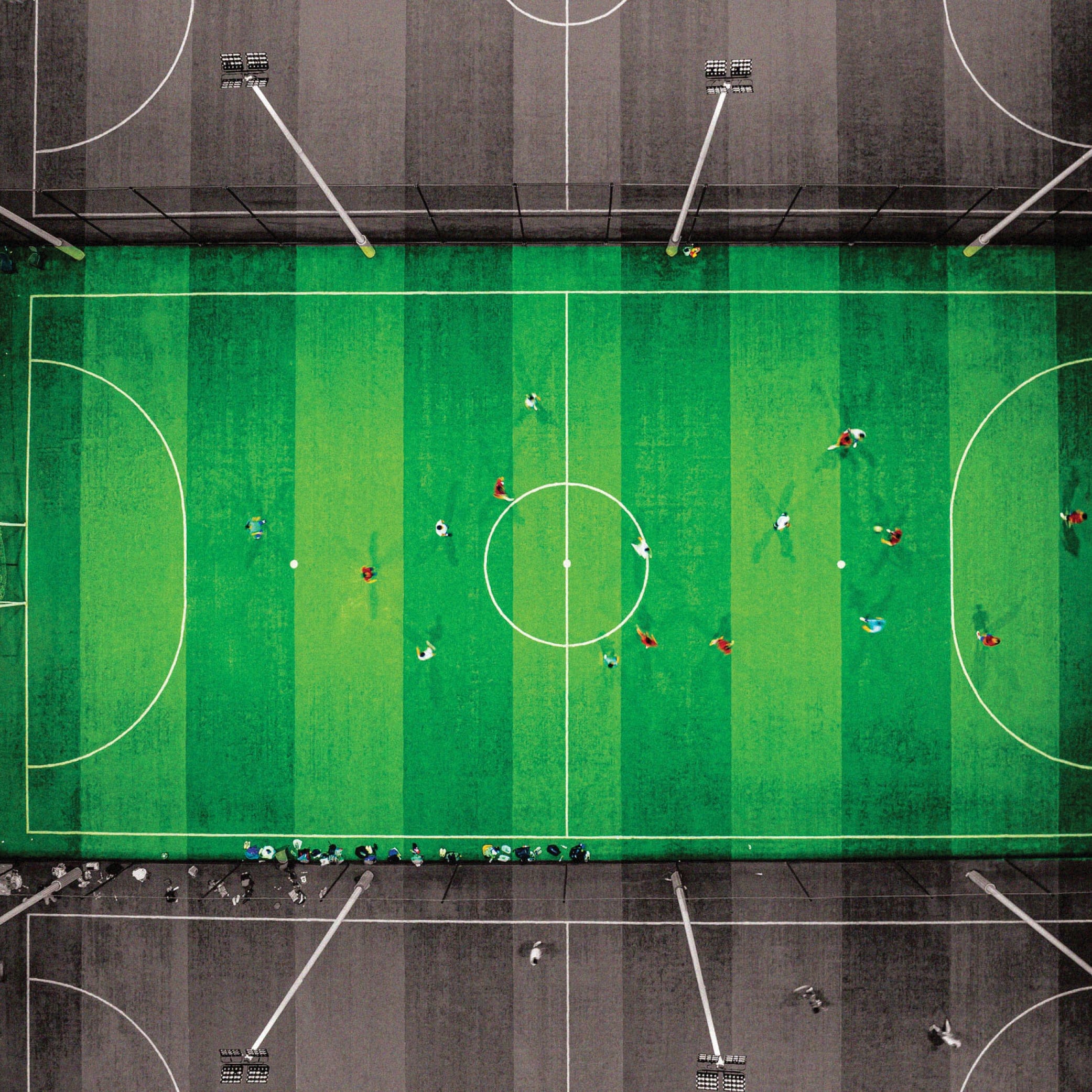 A mini soccer pitch captured directly from above. People are playing in the field.