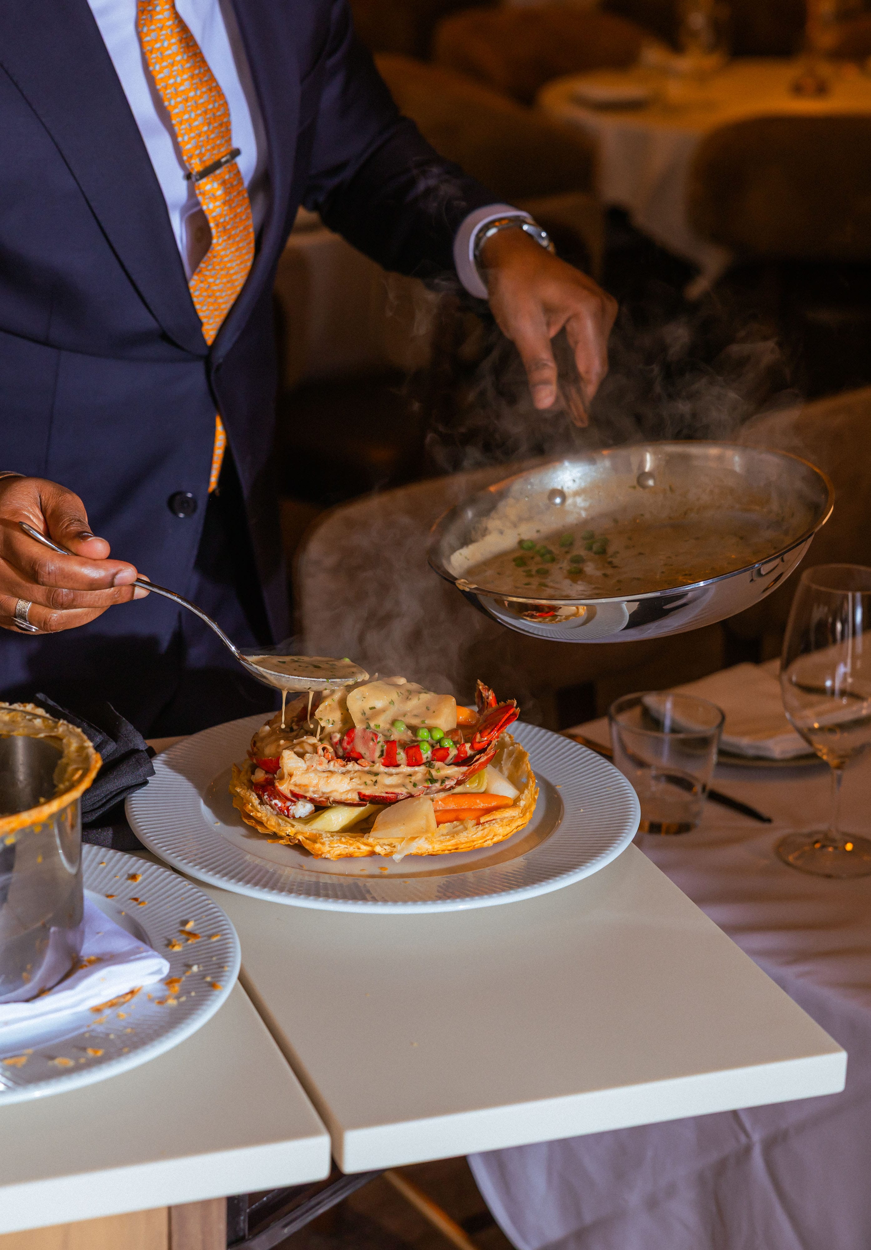 A server drizzling sauce over a meal