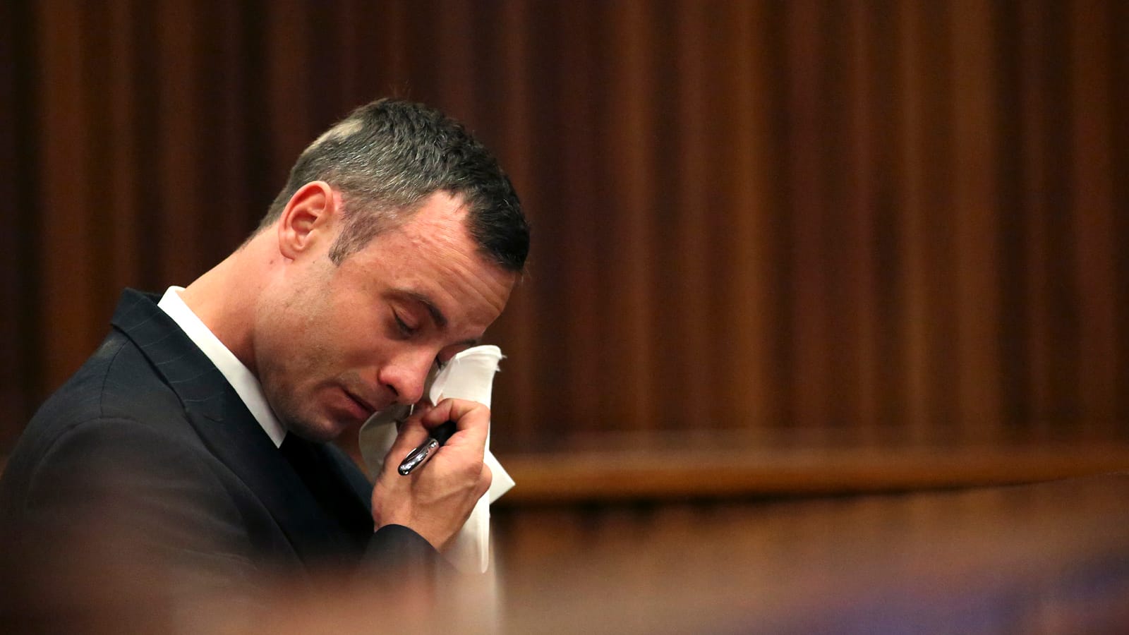 Olympic and Paralympic track star Oscar Pistorius reacts as he sits in the dock during his trial for the murder of his girlfriend Reeva Steenkamp, in Pretoria