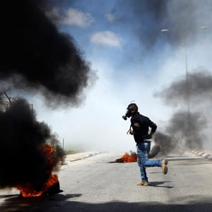 Palestinian protester runs during clashes with Israeli troops outside Israel's Ofer military prison near Ramallah