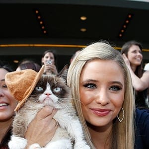 Grumpy Cat gets her photo taken with a fan as she arrives at the 2014 MTV Movie Awards in Los Angeles
