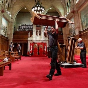 A worker carries a bench while preparing the Senate chamber on Parliament Hill in Ottawa