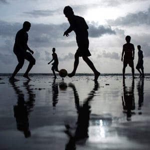 People are silhouetted as they play football at a beach along the Arabian Sea in Mumbai