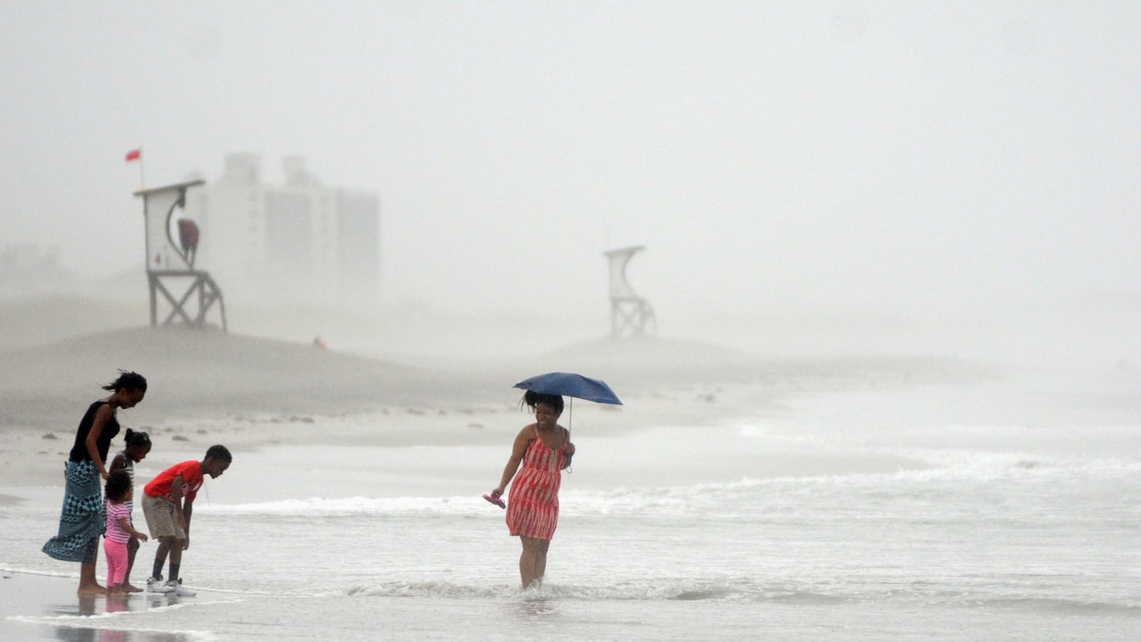 Beach goers at Wrightsville Beach, N.C., stand in the water Thursday, July 3, 2014. Residents along the coast of North Carolina are bracing for the arrival of the Hurricane Arthur, a category one storm. (AP Photo/Wilmington Star-News, Mike Spencer)