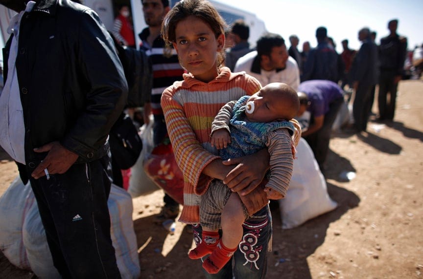 Rula, an eight-year-old Syrian Kurdish refugee girl holding her three-month-old brother Ciwan, waits for transportation after crossing into Turkey near the southeastern Turkish town of Suruc in Sanliurfa province