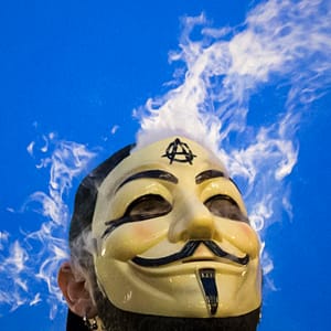 Vapor passes through a Guy Fawkes mask as a man smokes while joining supporters of the Anonymous movement who were taking part in the global "Million Mask March" protests in Union Square, New York