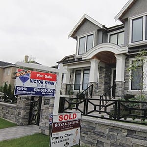 Realtors' signs are hung outside a newly sold property in a Vancouver neighborhood