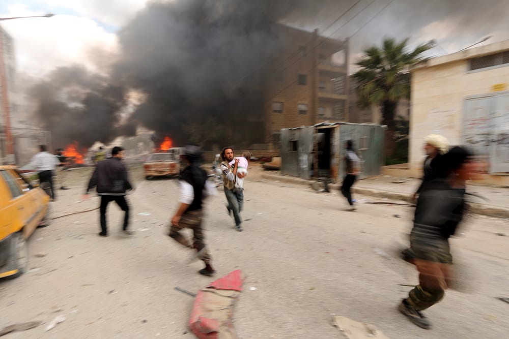 A man runs with an injured child at a damaged site after what activists said was shelling by forces loyal to Syria's president Bashar al-Assad on Al-Dubeit neighborhood in Idlib city