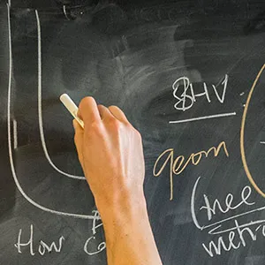 A mathematician uses Hagoromo chalk to write on a chalkboard. (Photograph by Satyan L. Devadoss)