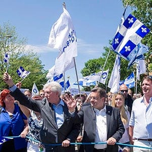 Bloc Quebecois Leader Gilles Duceppe (left to right), Montreal Mayor Denis Coderre and Parti Quebecois Leader Pierre Karl Peladeau along with his partner Julie Snyder wave to the crowd during the annual St-Jean- Baptiste Day parade in Montreal, Wednesday, June 24, 2015. (Graham Hughes/CP)