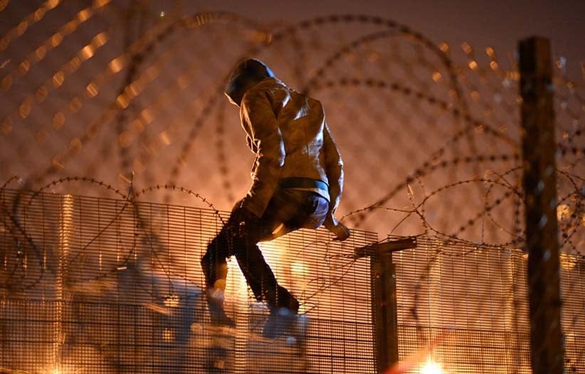A migrants camped out in Calais, attempts to climb a security fence near refugee camp of Calais, France on August 3, 2015. More than 2 thousands migrants waiting at Calais forests, hoping to get to Britain, camp out in Calais, on August 3, 2015. (Mustafa Yalcin/Anadolu Agency/Getty Images)