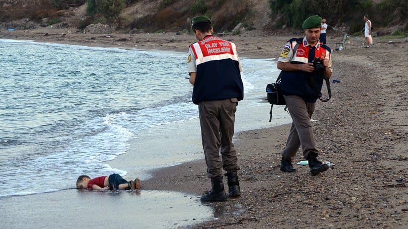 Paramilitary police officers investigate the scene before carrying the lifeless body of Aylan Kurdi, 3, after a number of migrants died and a smaller number were reported missing after boats carrying them to the Greek island of Kos capsized, near the Turkish resort of Bodrum early Wednesday, Sept. 2, 2015. AP