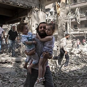 A Syrian man carries his two girls as he walks across the rubble following a barrel bomb attack on the rebel-held neighbourhood of al-Kalasa in the northern Syrian city of Aleppo on September 17, 2015. Once Syria's economic powerhouse, Aleppo has been ravaged by fighting since the rebels seized the east of the city in 2012, confining government forces to the west. (Karam Al-Masri/AFP/Getty Images)