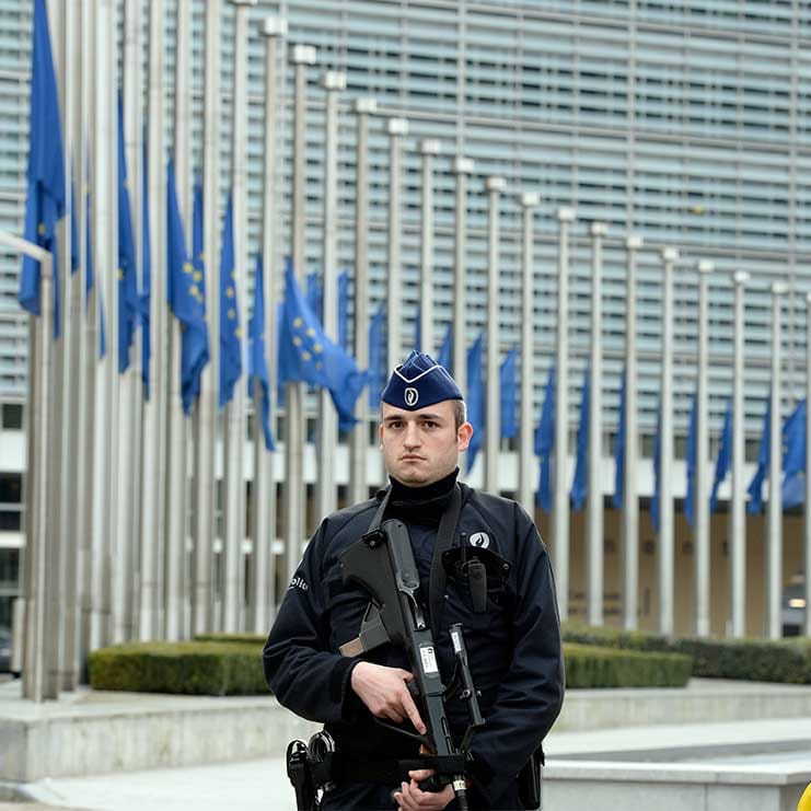 A Belgian Police officer stands guard in front of the European Union Commission headquarter in Brussels where the European flags are seen at half mast, after the terrorists attacks at Brussels airport and in the Brussels metro, 22/03/2016. (Thierry Charlier/Camera Press/Redux)