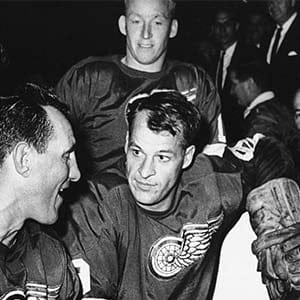Gordie Howe, Detroit Red Wings star forward, is surrounded by teammates as he kneels at boards after scoring his 544th goal and tieing the National Hockey League all-time record on Oct. 27, 1963 in Detroit. Howe’s goal equaled the record held by former Montreal Canadiens star Maurice Richard and came against his team on Detroit ice. From left: Larry Jeffrey, Bill Gadsby, Howe, and Terry Sawchuck. Behind Howe is Alex Faulkner. (Alvin Quinn/AP)