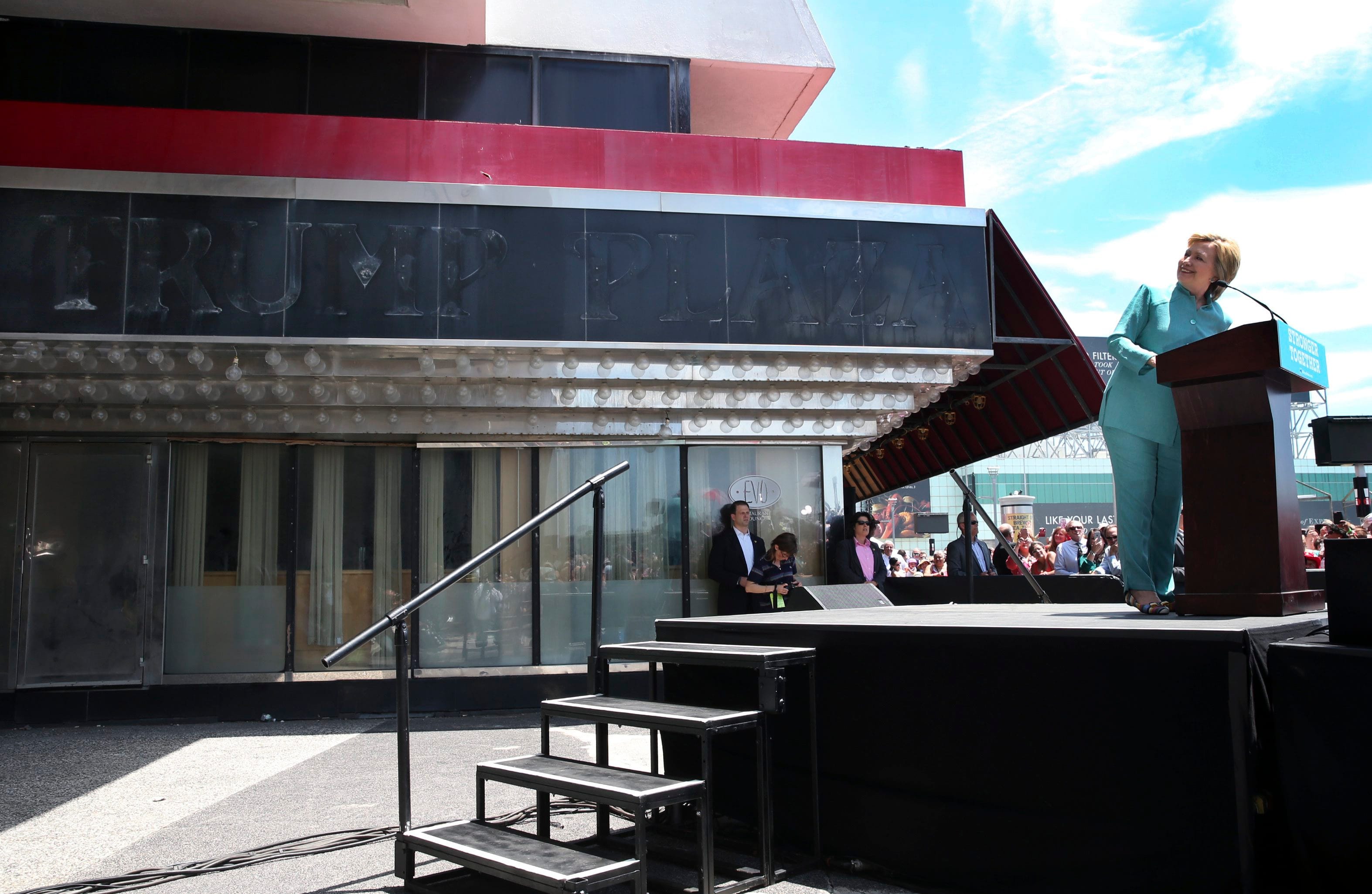 Democratic presidential candidate Hillary Clinton looks back at the faded sign of the former Trump Plaza as she speaks in Atlantic City, N.J., Wednesday, July 6, 2016. Trump Plaza closed permanently on Sept. 16, 2014. (AP Photo/Mel Evans)
