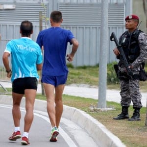 Police security officer is pictured as athlets walk at the Olympic Village ahead of the Rio 2016 Olympic Games. (Alexander Hassenstein/Getty)