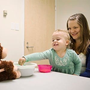 Toddler Gloria Slevinsky sits on her mother Janine Slevinsky's lap across from Kiley Hamlin (left), Canada Research Chair of Developmental Psychology, at UBC in Vancouver. Hamlin's research studies babies and toddlers and sharing. In this experiment Slevinsky was provided with treats that she ccould choose to share with a stuffed toy. (Photograph by Della Rollins)