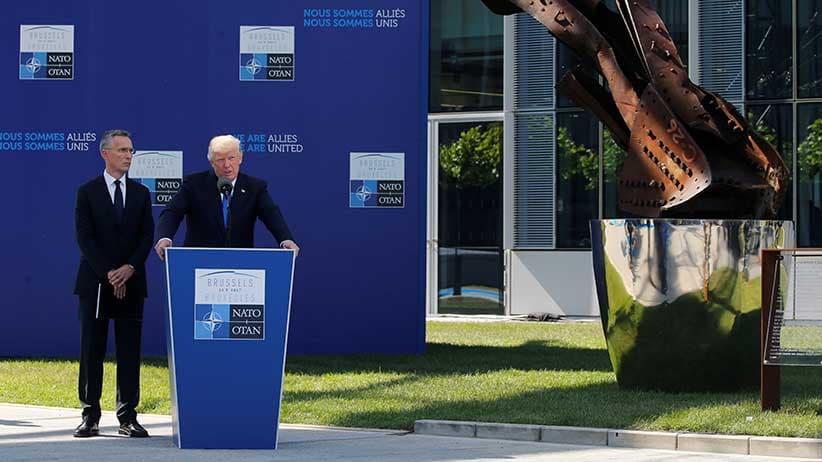 U.S. President Donald Trump speaks beside NATO Secretary General Jens Stoltenberg at the start of the NATO summit