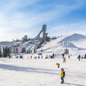 Calgary, Canada - March 1, 2015: People enjoying the skiing at Canada Olympic Park on March 1, 2015 in Calgary, Alberta. Visible are skiers at the base of the hill. Ski jump towers are on the top left.