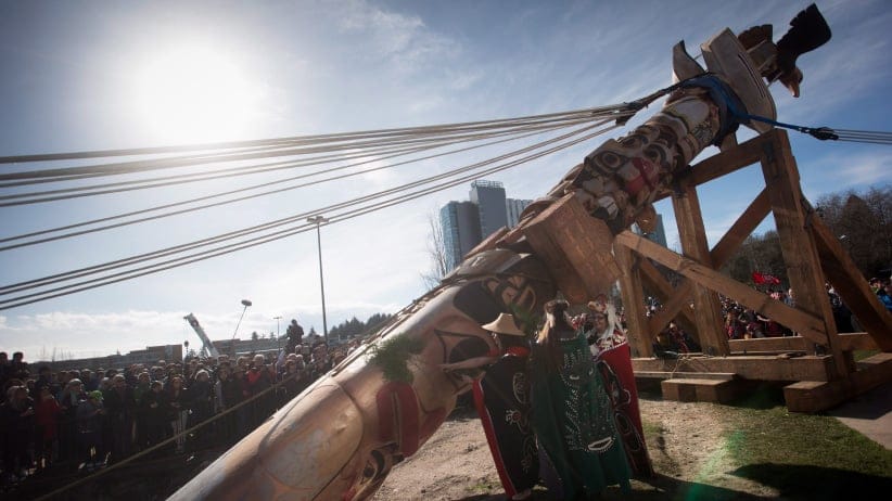 First Nations women bless a Reconciliation Pole before its raising at the University of British Columbia in Vancouver, B.C., on Saturday, April 1, 2017. The 17-metre red cedar pole tells the story of the time before, during and after the Indian residential school system. Thousands of copper nails representing thousands of Indigenous children who died in Canada's residential schools were hammered into the pole by survivors, affected families, school children and others. The totem pole faces the future site of the Indian Residential School History and Dialogue Centre. (Darryl Dyck/CP)