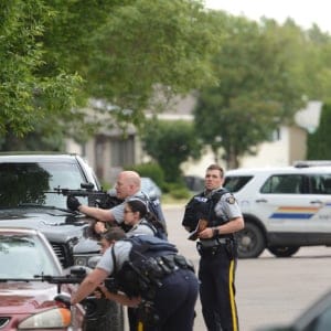 Police take cover behind vehicles with guns drawn during standoff in North Battleford in June, 2017. (Greg Higgins/battlefordsNOW)