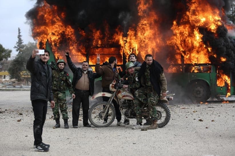Cadets, trainers, and members of the military council takes a selfie with an empty exploded bus used by the government to transfer fighters to Idlib during a training drill, in Jaysh al-Islam Military Academy, in an undisclosed location, rebel-held Eastern Ghouta, outskirts of Damascus, Syria, 16 January 2017. In February 2016, Jaysh al-Islam announced the establishing of a Military Academy, after efforts from its former leader Zahran Alloush who died in December 2015. The academy is conducted in cooperation with the Military Council for Damascus and its Suburbs. The goals of the academy is to graduate fighters with thorough background in fighting tactics, and to enlist its graduates in the newly formed Unified Syrian National Army called for by various rebel groups. (Mohammed Badra/EPA/CP)