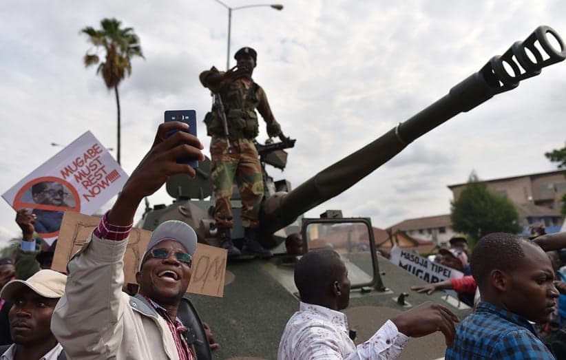 A man takes a selfie-picture of a Zimbabwean Defence Force soldier standing on a tank during a march in the streets of Harare, on November 18, 2017 to demand to the 93 year-old Zimbabwe's president to step down. Zimbabwe's president clings to office, the military is in power and the much-feared ZANU-PF party still rules -- but Zimbabweans put such issues aside on November 18, 2017 to happily embrace what they hope is a new era for the country. (AFP/Getty Images)