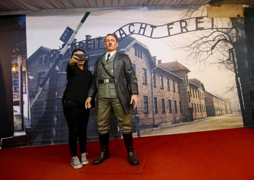 This photograph taken on November 10, 2017 shows an Indonesian woman take a selfie with a life-size wax sculpture of Adolf Hitler at a museum in Yogyakarta. An Indonesian museum that allowed visitors to take selfies with a life-size wax sculpture of Hitler against a backdrop of Auschwitz concentration camp has removed the exhibit following international outrage, the manager said on November 11. (Henryanto/AFP/Getty Images)
