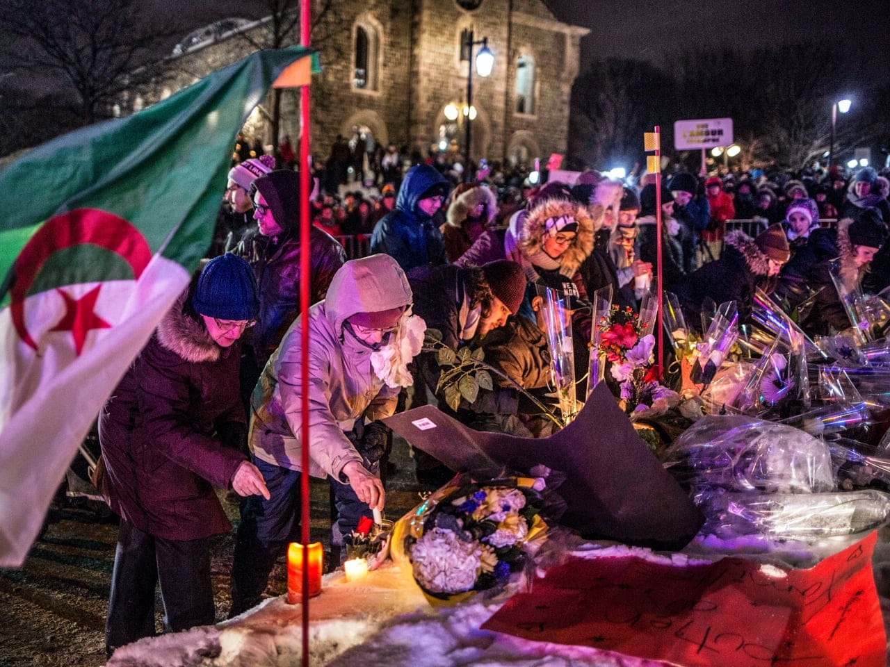 Mourners place candles and flowers at a memorial for the victims, following the shooting. Photo by Roger Lemoyne.