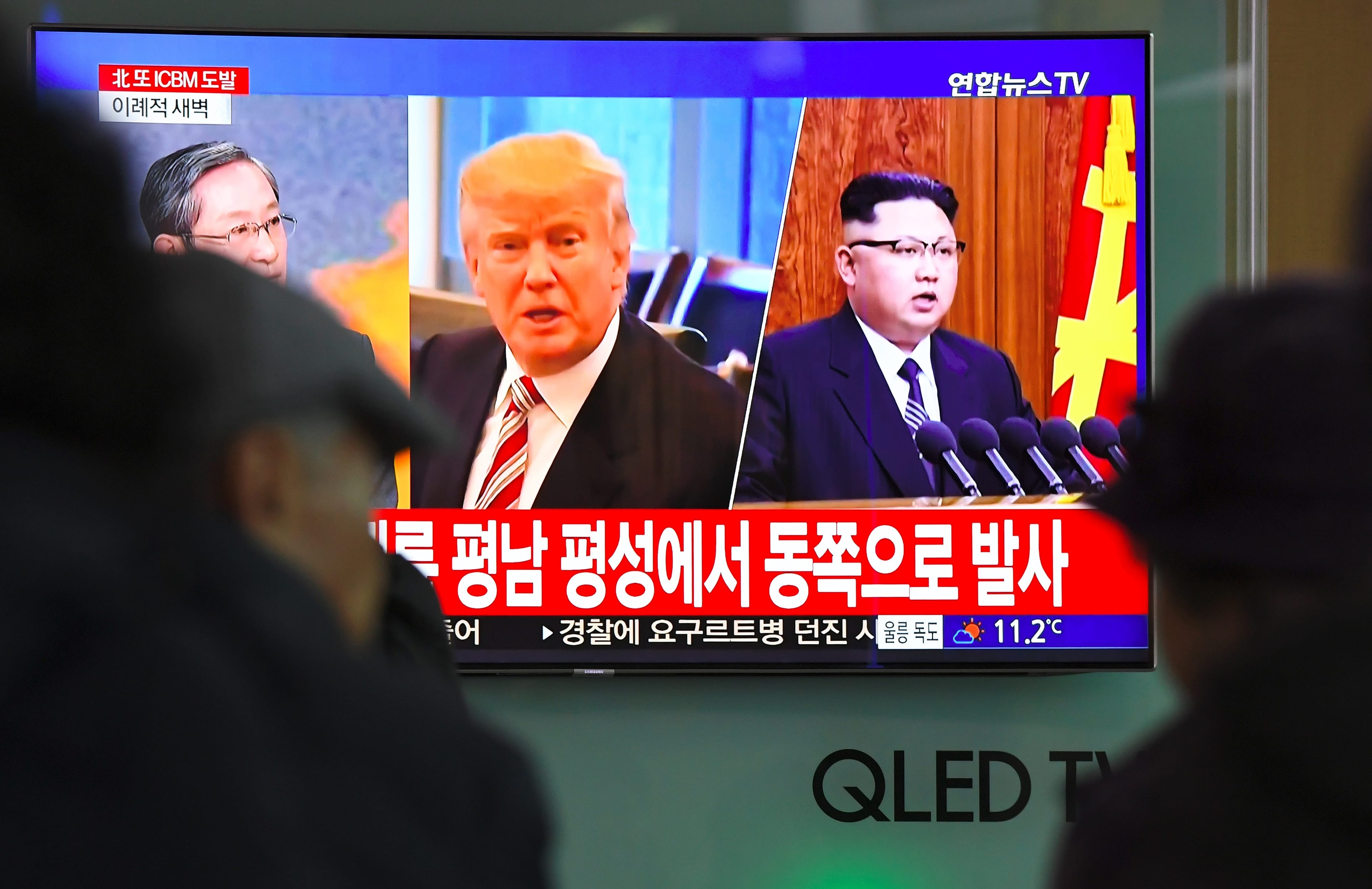 People watch a television news screen showing pictures of US President Donald Trump (C) and North Korean leader Kim Jong-Un (R) at a railway station in Seoul on Nov. 29, 2017.
(JUNG YEON-JE/AFP/Getty Images)