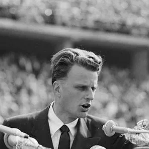 FILE - In this June 27, 1954 file photo, Evangelist Billy Graham speaks to over 100,000 Berliners at the Olympic Stadium in Berlin, Germany. Graham, who died Wednesday, Feb. 21, 2018, at his home in North Carolina's mountains at age 99, reached hundreds of millions of listeners around the world with his rallies and his pioneering use of television. Graham's body will be brought to his hometown of Charlotte on Saturday, Feb. 24, as part of a procession expected to draw crowds of well-wishers. (AP Photo/Werner Kreusch, File)