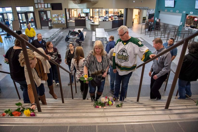 Humboldt mayor Rob Muench, in the Broncos jersey, along with other mourners lay down flower on the stairs that enter to Elgar Petersen Arena, home of the Humboldt Broncos, in Humboldt, Sask., on Saturday, April 7, 2018. RCMP say 14 people are dead and 14 people were injured Friday after a truck collided with a bus carrying a junior hockey team to a playoff game in northeastern Saskatchewan. Police say there were 28 people including the driver on board the Humboldt Broncos bus when the crash occurred at around 5 p.m. on Highway 35 north of Tisdale. THE CANADIAN PRESS/Liam Richards