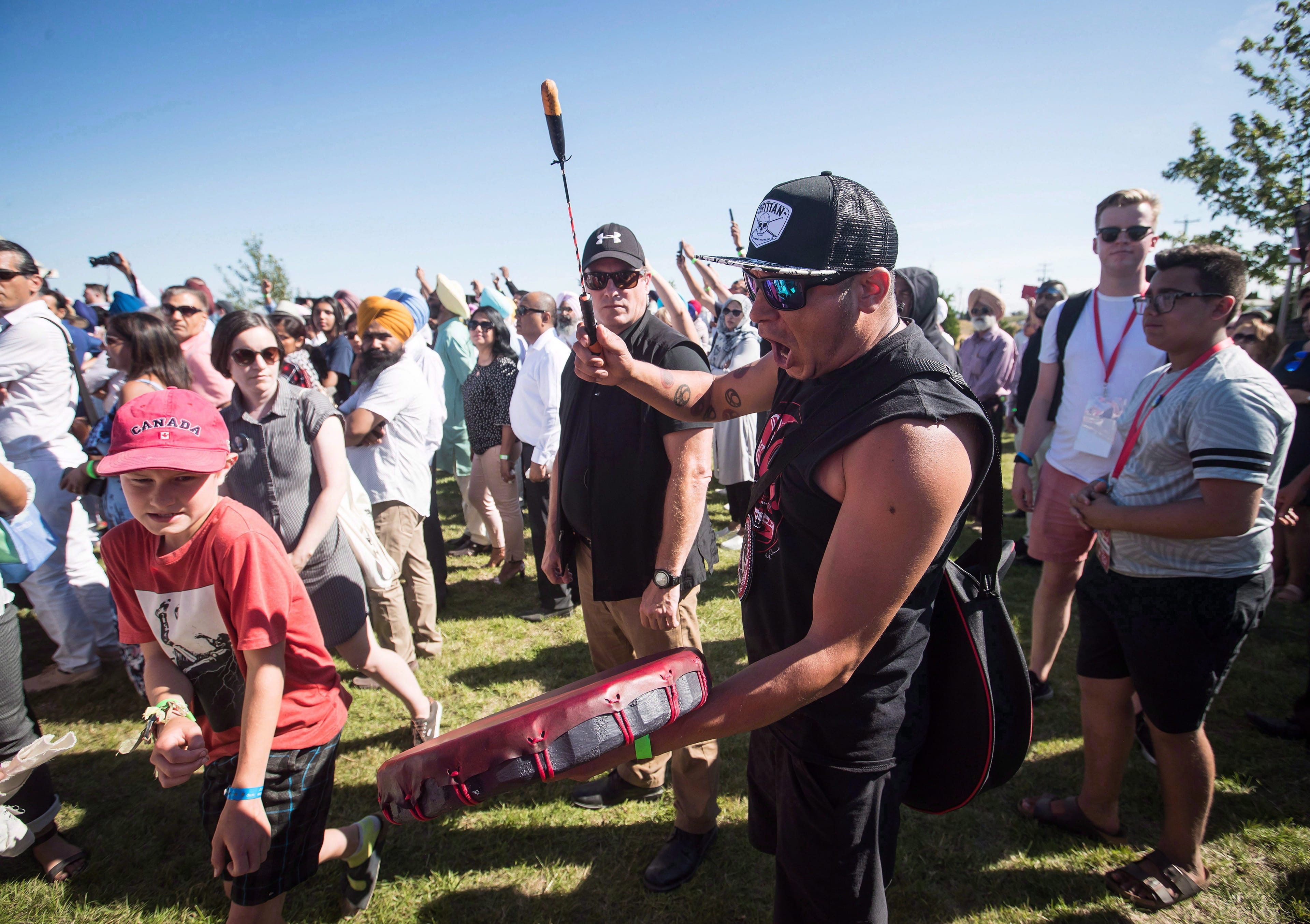 A member of the Tsleil-Waututh First Nation sings in protest as Prime Minister Justin Trudeau speaks at a barbecue in Delta, B.C., on Sunday Aug. 5, 2018. (THE CANADIAN PRESS/Darryl Dyck)