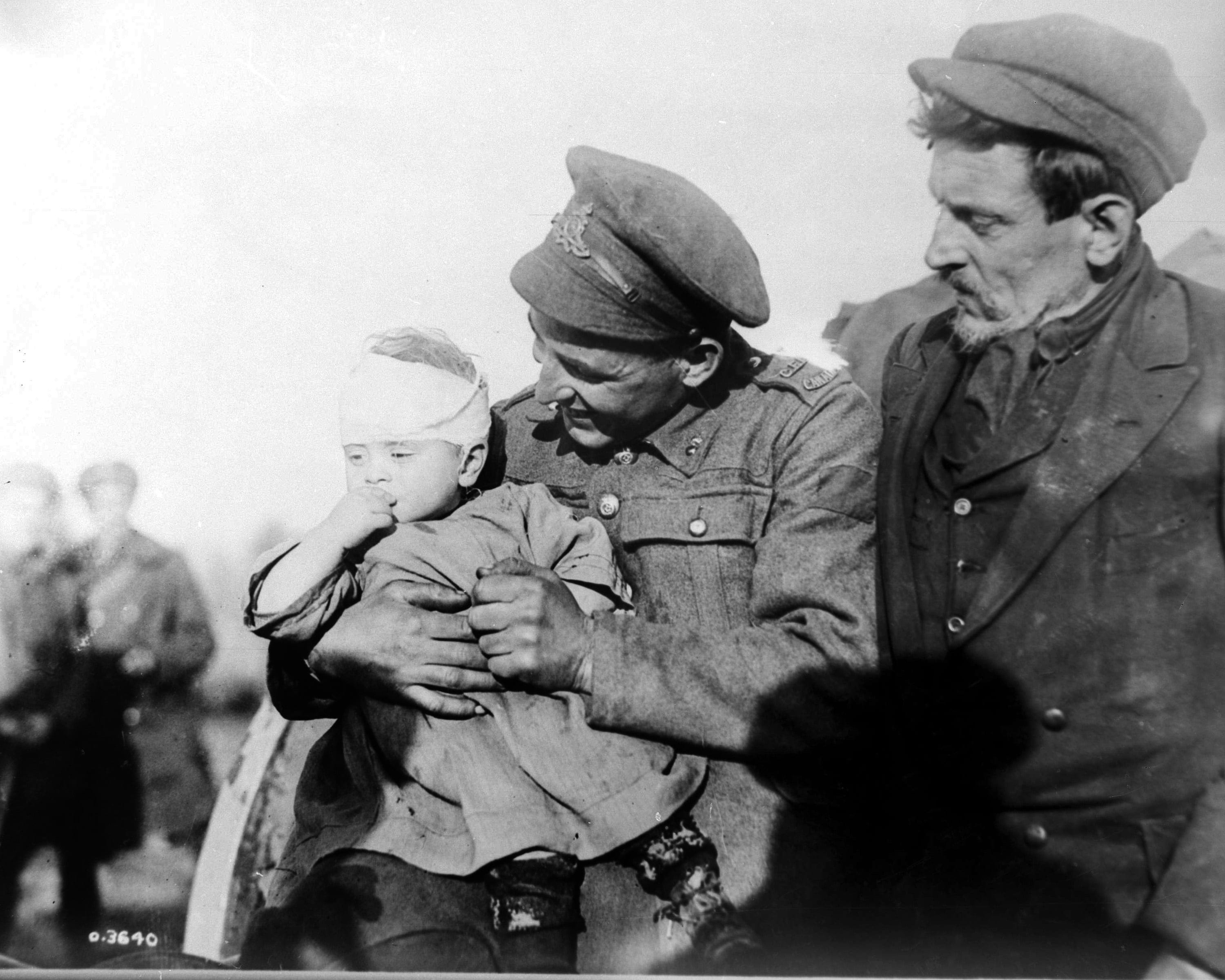 In this undated file photo, a World War I Canadian soldier, centre, comforts a Belgian child whose mother was killed by an enemy shell in Mons, Belgium. The child, who was in its mother's arms, was wounded in the attack. The father is seen at right. (AP/CP)