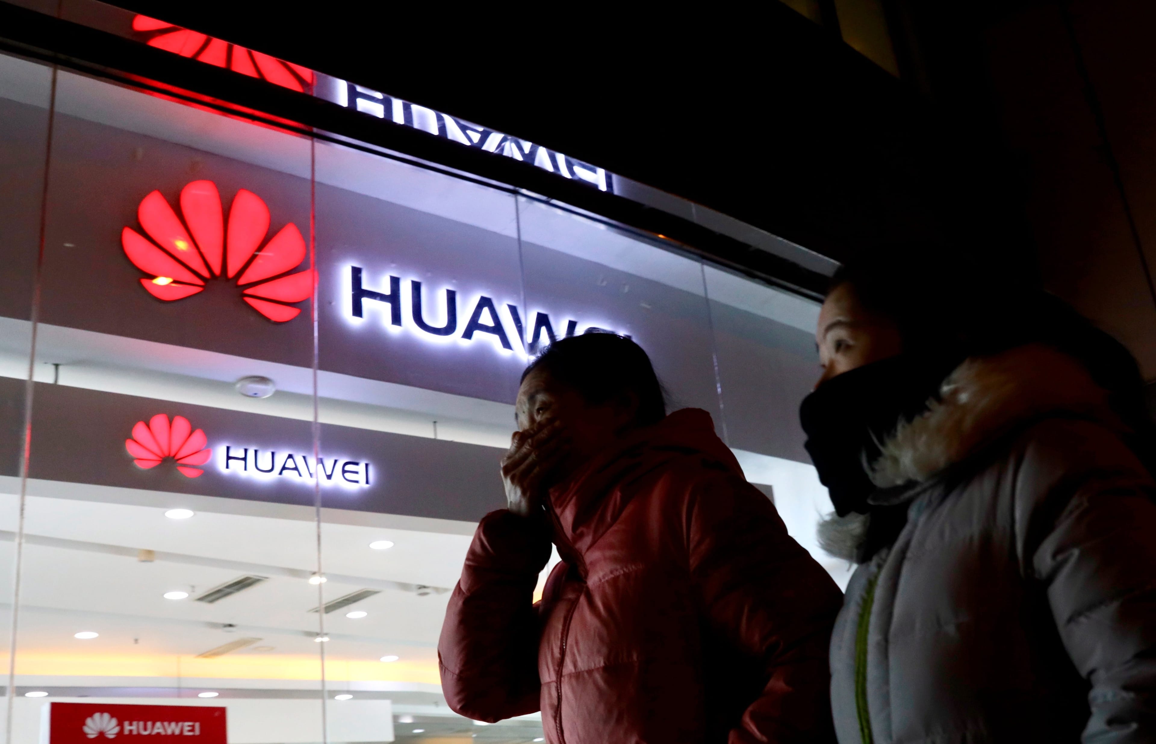 Women walk past a Huawei retail shop in Beijing Thursday, Dec. 6, 2018. China on Thursday demanded Canada release a Huawei Technologies executive who was arrested in a case that adds to technology tensions with Washington and threatens to complicate trade talks. (AP Photo/Ng Han Guan)