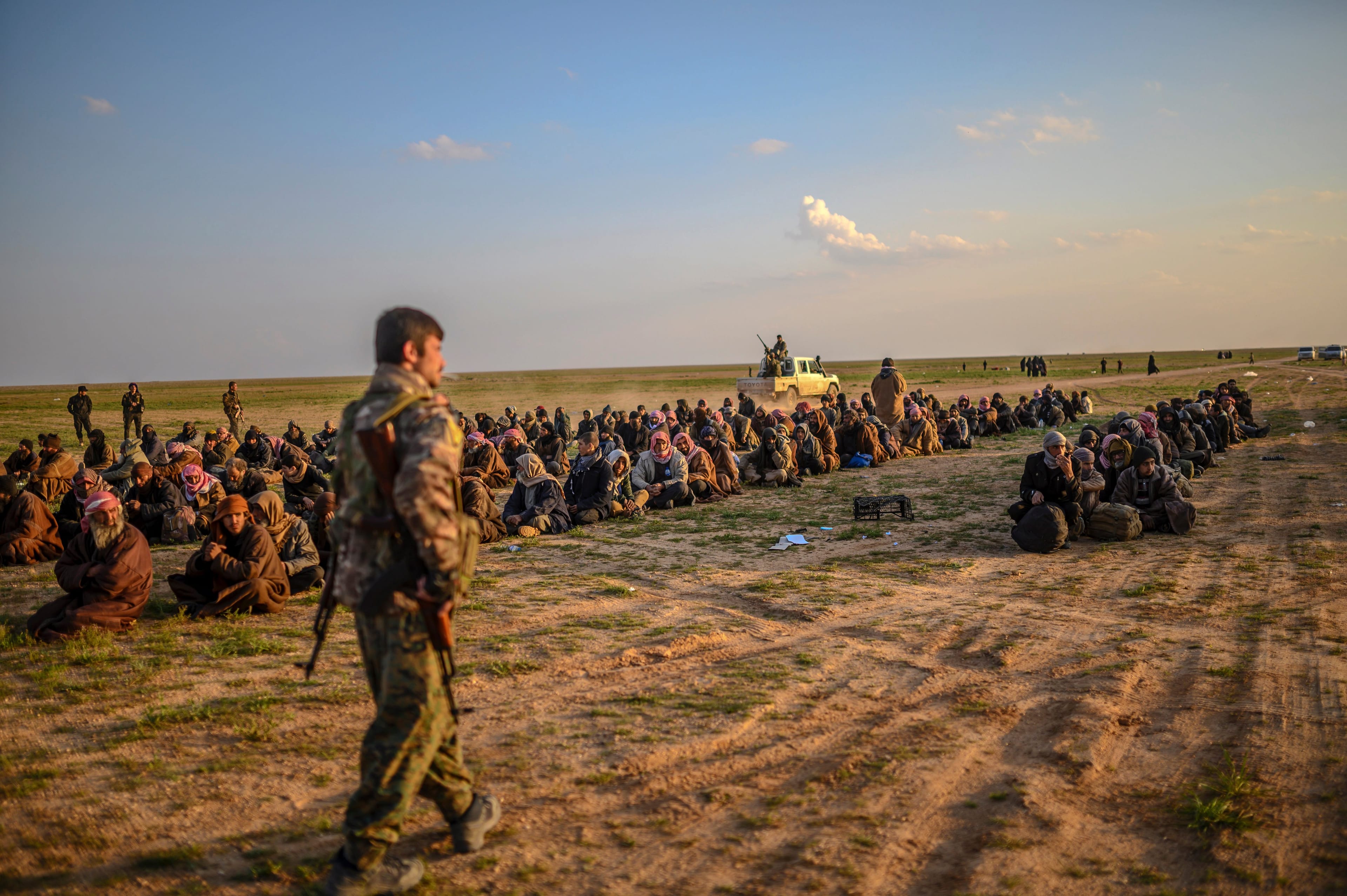 Men suspected of being ISIS fighters wait to be searched by members of the Kurdish-led Syrian Democratic Forces in Syria's northern Deir Ezzor province on Feb. 22, 2019. (Bulent Kilic/AFP/Getty Images)