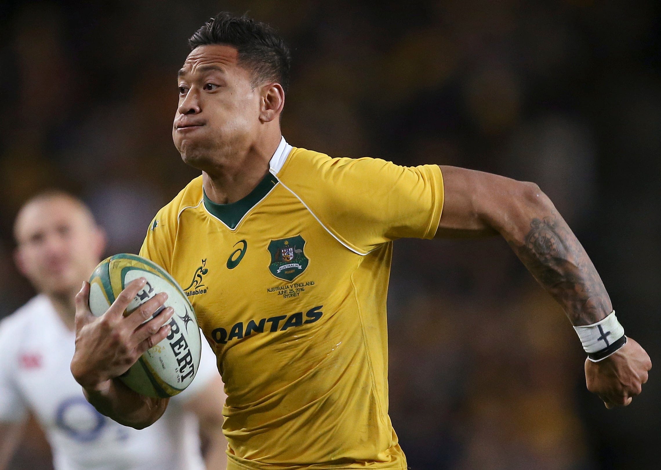 In this June 25, 2016, photo, Australian rugby union player Israel Folau, wearing tape on his wrist adorned with a cross, runs toward the try line to score against England during their rugby union test match in Sydney. Folau, one of the sport's top players, published a message on his Instagram account that said "drunks, homosexuals, adulterers, liars, fornicators, thieves, atheists, idolators. Hell awaits you." (AP Photo/Rick Rycroft)