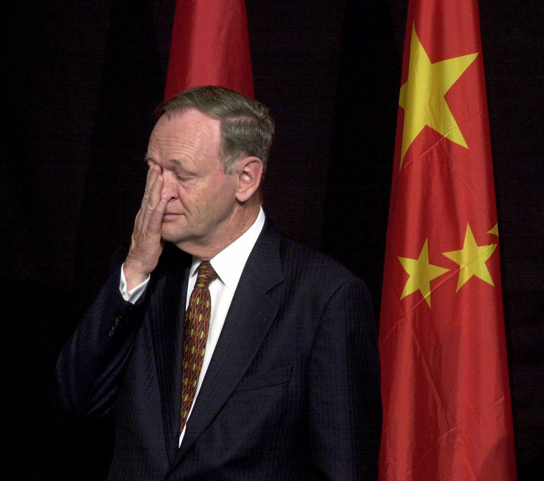 Canadian Prime Minister Jean Chretien, standing next to the Chinese flag, wipes his eye while attending a bilateral commercial contracts and agreements signing ceremony in Hong Kong Saturday, Feb. 17, 2001. (Anat Givon/AP)