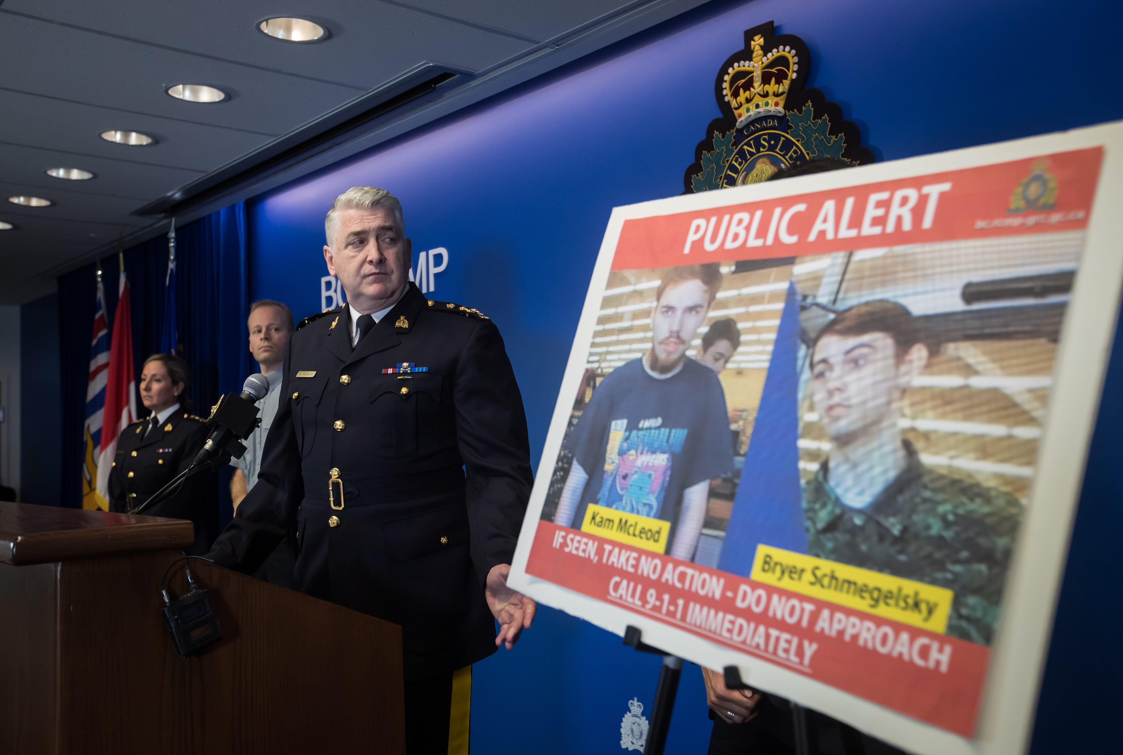 Security camera images recorded in Saskatchewan of Kam McLeod, 19, and Bryer Schmegelsky, 18, are displayed as RCMP Assistant Commissioner Kevin Hackett steps away from the podium after speaking during a news conference in Surrey, B.C., on Tuesday July 23, 2019. (Darryl Dyck/CP)
