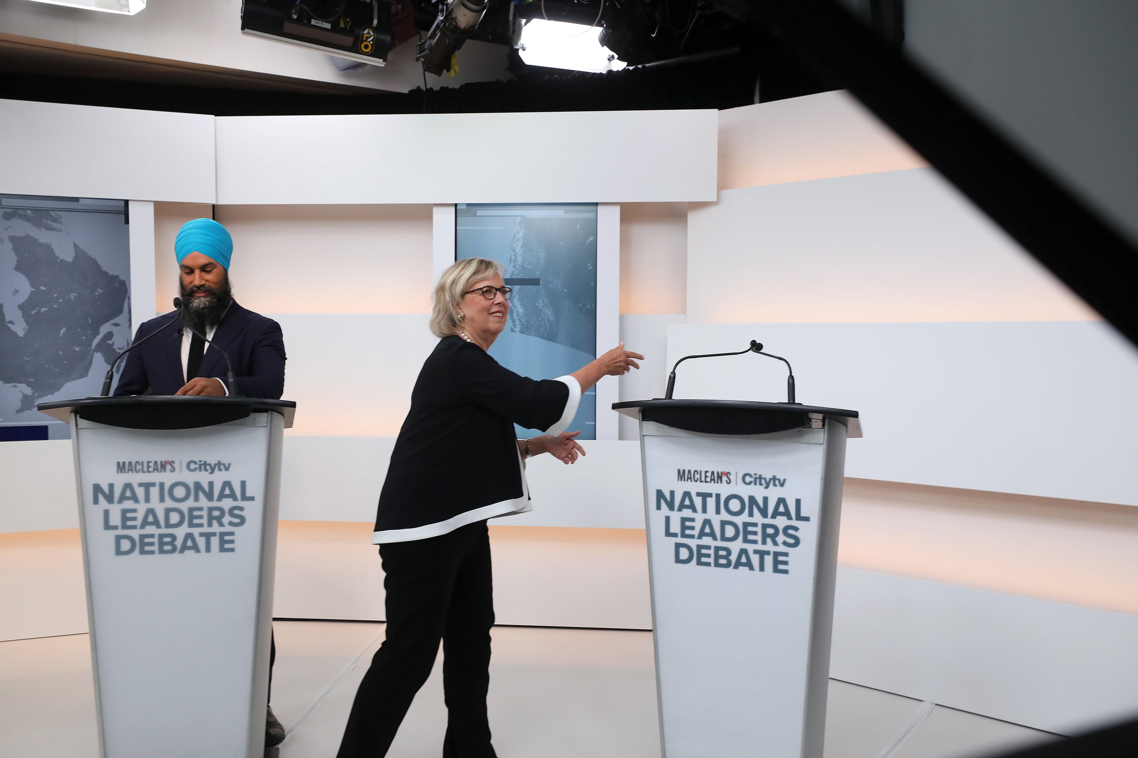 May mimes shaking hands with Justin Trudeau at his empty podium (Photograph by Cole Burston)