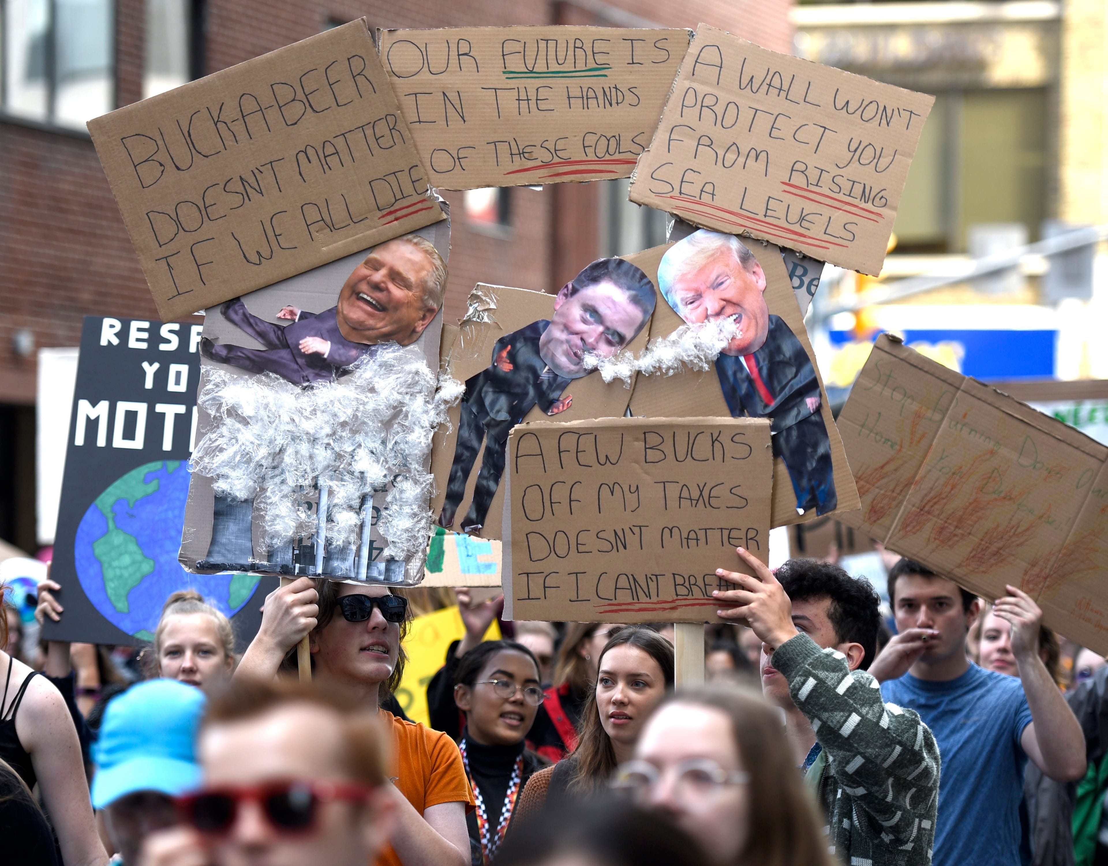 People hold signs depicting Ontario Premier Doug Ford, Conservative leader Andrew Scheer and U.S. President Donald Trump as they march in Ottawa as part of a Global Climate Strike, protesting against climate change and inaction, on Friday, Sept. 27, 2019. THE CANADIAN PRESS/Justin Tang