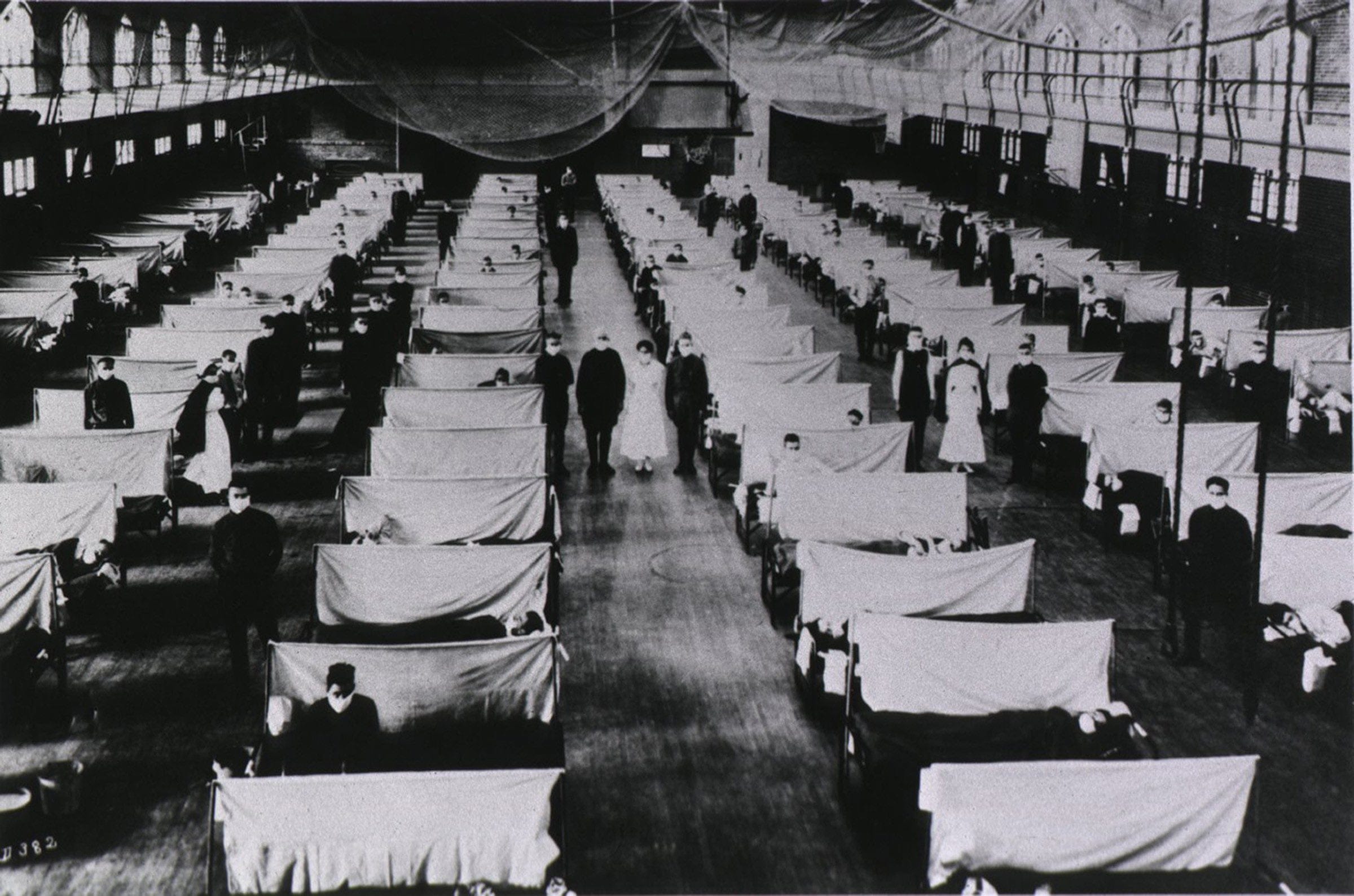 Spanish Flu Epidemic 1918-19. U.S. school gymnasium converted into an flu ward with patients' beds are separated by screens and masked health workers. An estimated 25% of the US population contracted the flu and over 500,000 died. (CP/Courtesy of Everett Collection)